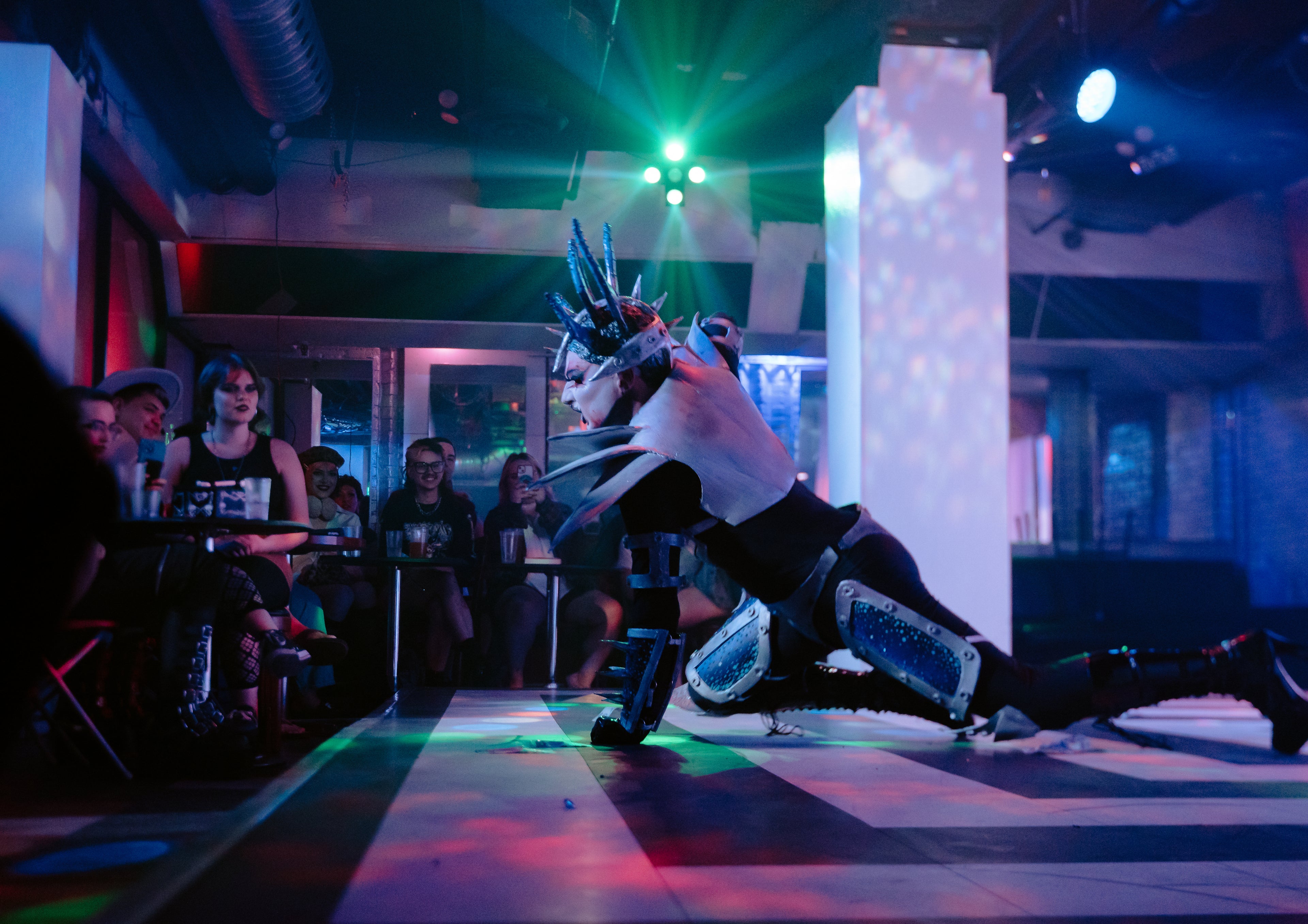 Emmonia performing floor work on the stage at Evolution Wonderlounge in a spiked outfit
